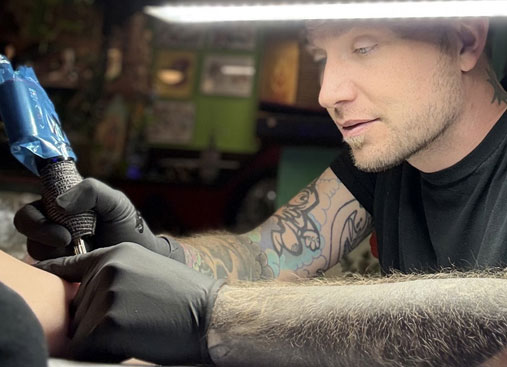 Travis the tattoo artist at work, focused and precise.